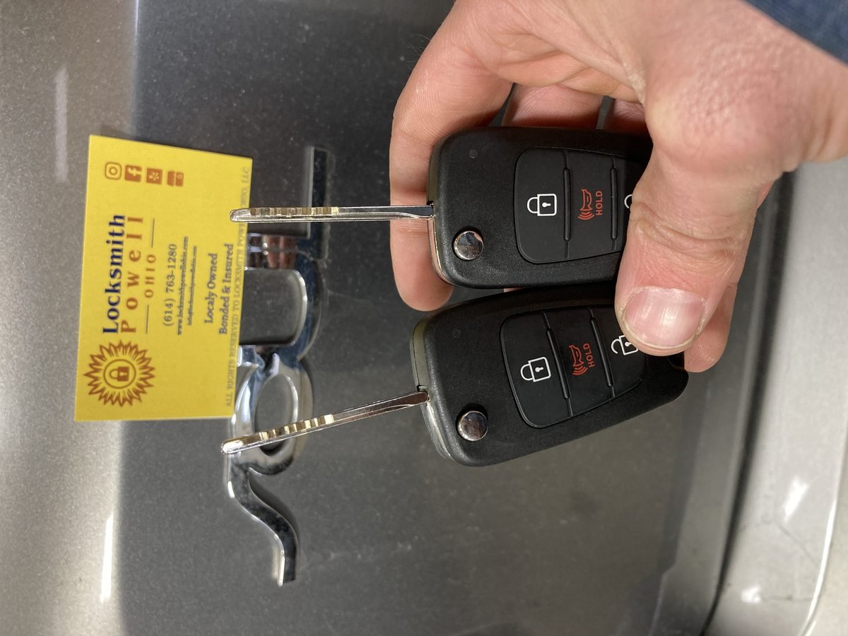 Locksmith Powell Ohio flip key replacement showing two cut and programmed car keys with business card on vehicle in Powell Ohio