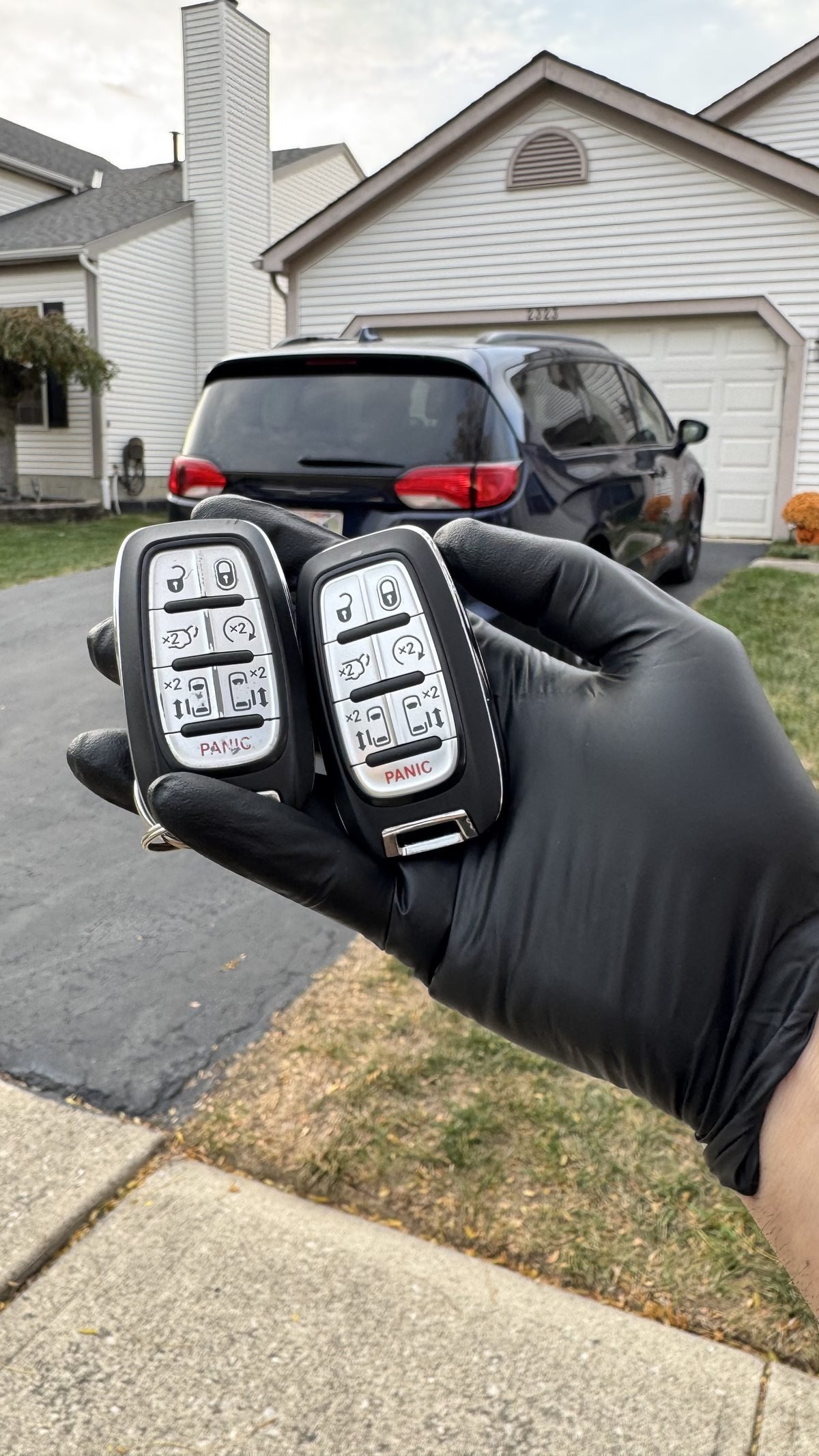 Locksmith Powell Ohio technician holding two Chrysler key fobs after replacement and programming at a Powell Ohio residential driveway